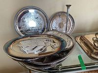 Stack of seven silver-plated trays and platters with intricate engraving and patina, plus one sterling silver vase