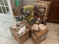 Yellow KitchenAid K5SS stand mixer with accessories and original box set on cardboard boxes.