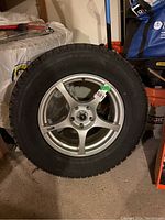 Front view of an alloy rim mounted with a snow tire, showing rim spoke design and tire tread.