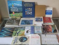 Wide view showing all books arranged on a table, titles include atlas, religion, sports, and educational books.