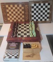 Three chess boards displayed vertically: two folding boards with intricate borders and a floral patterned square board with reddish-brown carved chess pieces set up for play.