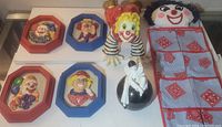Top view of five clown wall plaques arranged horizontally on glass surface showing detailed faces and colors.