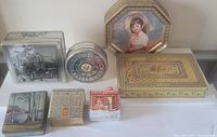 Overview of six assorted vintage collector tins with different shapes and scenic or portrait prints