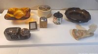 All items displayed on white board including ceramic ashtrays, wooden and metal lighters, marble pipe ashtray, and rotating ashtray.