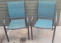 Front view of two outdoor patio chairs with blue mesh seats and backs and dark brown metal frames, placed against a wooden siding wall.