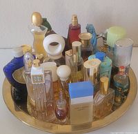 Perfume bottles arranged on a brass vanity tray, showing multiple shapes and colors of bottles.
