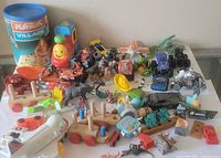 Overview of all small toy figures and pieces including vehicles, animals, and playset parts on a glass table.