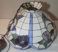 Side view of Tiffany style lamp shade showing stained glass floral and geometric design with attached hanging chain and wiring.