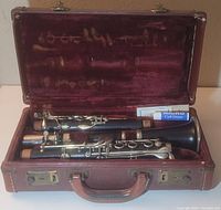 Vintage Whitehall clarinet disassembled and arranged inside a fitted case with red velvet lining. All standard parts present including barrel and mouthpiece along with cork grease tube.