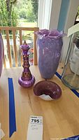 Photo shows the tall purple mottled vase with ruffled edges, the decorative purple and gold bottle with pointed stopper, and the small purple and white dish on a table.
