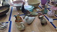 Wide view of ceramic figurines on table showing multiple birds and decorative items