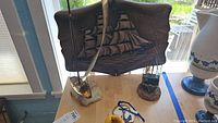Wooden wall plaque with brass ship silhouette shown on stand