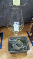 Overall shot showing large 20-inch clear glass vase and a plastic bin with assorted glass candle holders inside, dusty and needing cleaning.