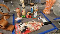 Overview photo of multiple Asian inspired wooden figurines and the decorative paddle on a grey surface with wood furniture around.