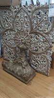 Angled view of the wooden floral wall art and part of the shelf base, showing distressed white and brown finish and detailed carvings.