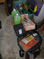 View showing two green jugs of MXC ATV wash, small brown paper package (engine gaskets), and assorted boxes and bags on a floor.