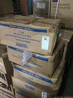 Three sealed cardboard cases stacked containing disposable coveralls, showing Global branding and model number.