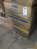 Stack of four sealed cardboard boxes labeled Global brand disposable coveralls, Model 708186XL, 25 per case, size XL, white color, elastic wrists/ankles.