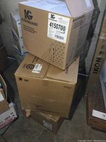 Three stacked cardboard boxes of disposable coveralls including Kleenguard brand visible on top box.