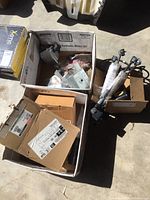 Boxes containing various Ford truck parts including retractors and shocks on concrete floor, some items in packaging