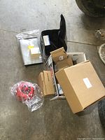 Overview of multiple boxes and items including battery bags, lighthouse topper, and sealed boxes on a concrete floor