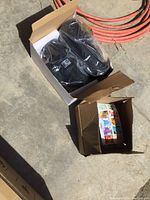 Photo showing black wall lights sealed in plastic inside a brown box and an open box containing multiple Air Wick Hawaii scent cartridges.