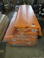 Stack of orange McCue mats in storage showing all sizes