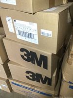 Stacked cardboard cases with 3M logos showing sealed packaging for respirator masks