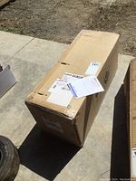 Sealed cardboard box labeled with shipping and auction tags, likely containing the strut assembly.