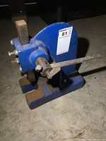 Front angled view of blue cast iron bearing press showing base, ram, and modified handle.