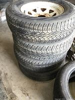 Stack of four white-painted steel wheels with tires