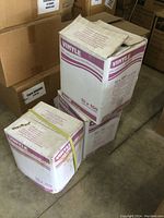 Three cardboard cases of vinyl exam gloves with purple print. Each case contains 10 boxes of 100 gloves. Boxes are sealed or secured with bands.