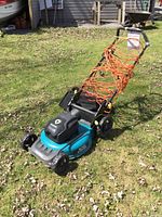 Full view of mower with extension cord wrapped on handle and grass bag installed