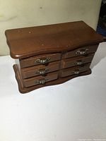 Wooden jewelry box front view showing six drawers with metal handles.