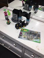 Overview of the Lego Duplo set including Batman, Joker, Robin minifigures, Gotham building blocks, and instruction booklet.