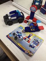 Mega Bloks Paw Patrol police cruiser set including cruiser, snowmobile, tower, and instruction booklet displayed on a white surface with mirror background.