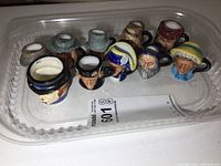 Top view of all 10 miniature Toby mugs arranged in plastic container.