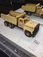 Front angled view of vintage yellow pressed steel Nylint dump truck showing condition and construction details