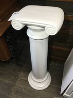 Front angle showing the white porcelain classical column plant stand with cylindrical shaft and scroll top.