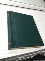 Green hardcover stamp album closed on white surface.