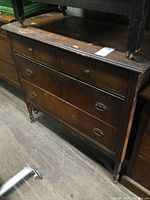 Front view of vintage wooden dresser showing four drawers with mixed handles and visible surface wear.