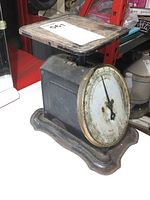 Side-angle view of vintage metal family counter scale showing its rectangular weighing platform, metal body, and round dial face with numbers and pointer.
