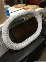 Front view of oval mirror with white wicker frame showing clear reflection and overall condition.