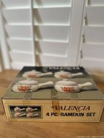 Original box top showing the four porcelain ramekins with handles and lids adorned with orange floral design.