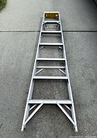 Full length view of the aluminum folding ladder placed flat showing structure and multiple rungs