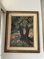 Front view of the vintage framed oil painting showing the forest tree with a fabric mat border and wooden frame.