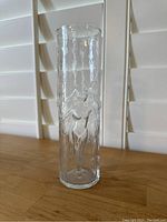 Front view of clear glass vase with embossed nude dancing women figures in relief wrapping around the body.
