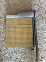 Top-down view of the guillotine paper cutter showing cutting surface, grid markings, and metal blade arm.