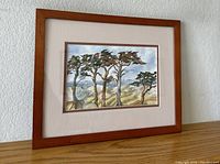 Front view of framed watercolor painting of savannah trees with visible landscape and sky details.