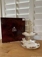 Two-tier cake stand displayed next to original Royal Albert box with flower pattern and gold handle